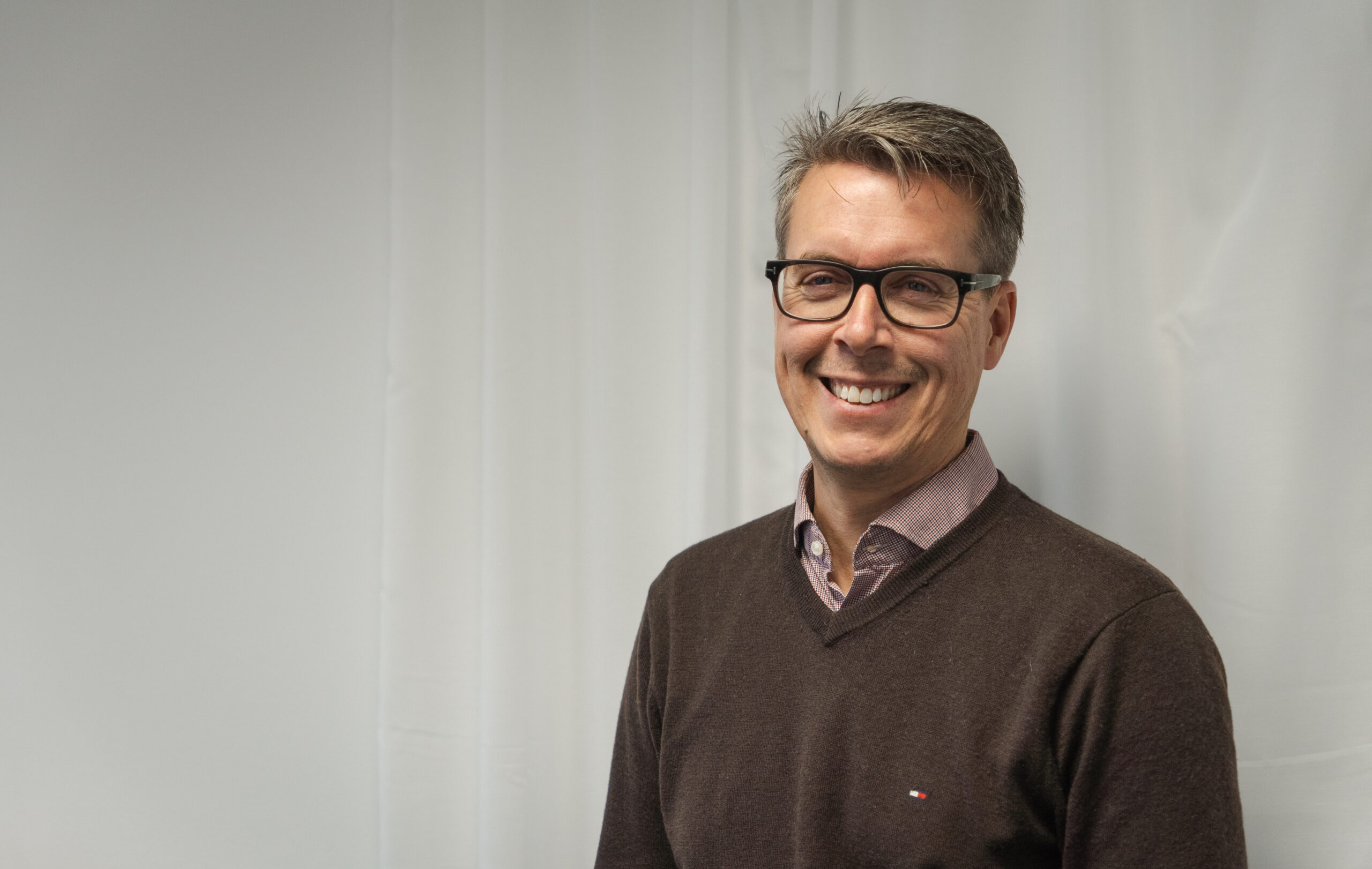 Mattias Fält, IT-specialist på Visionite, leende mot kameran i en fotostudio.
