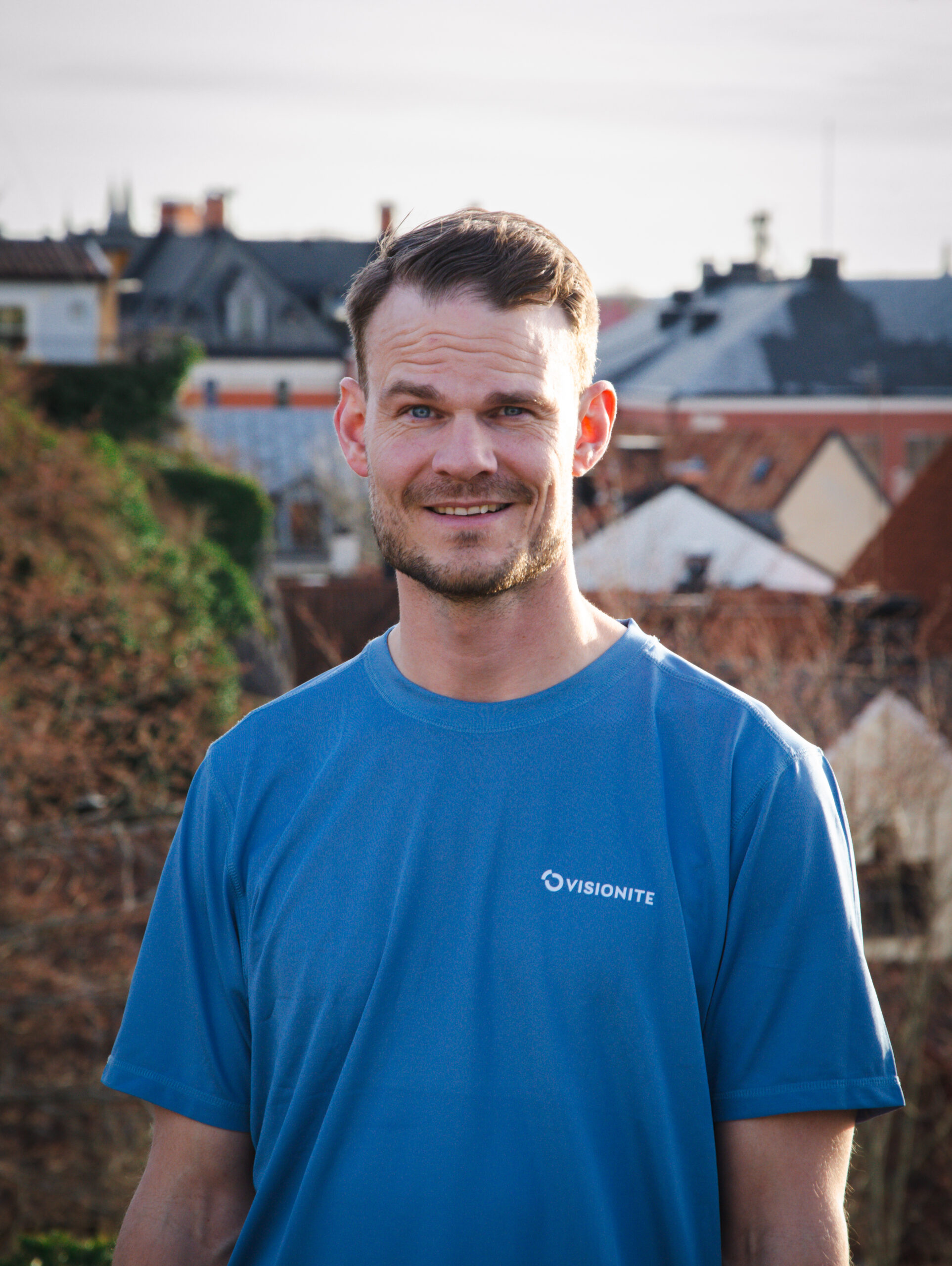 En porträttbild på Christian Olsson, VD Visionite Visby. Han ler ot kameran och har Visby i bakgrunden.