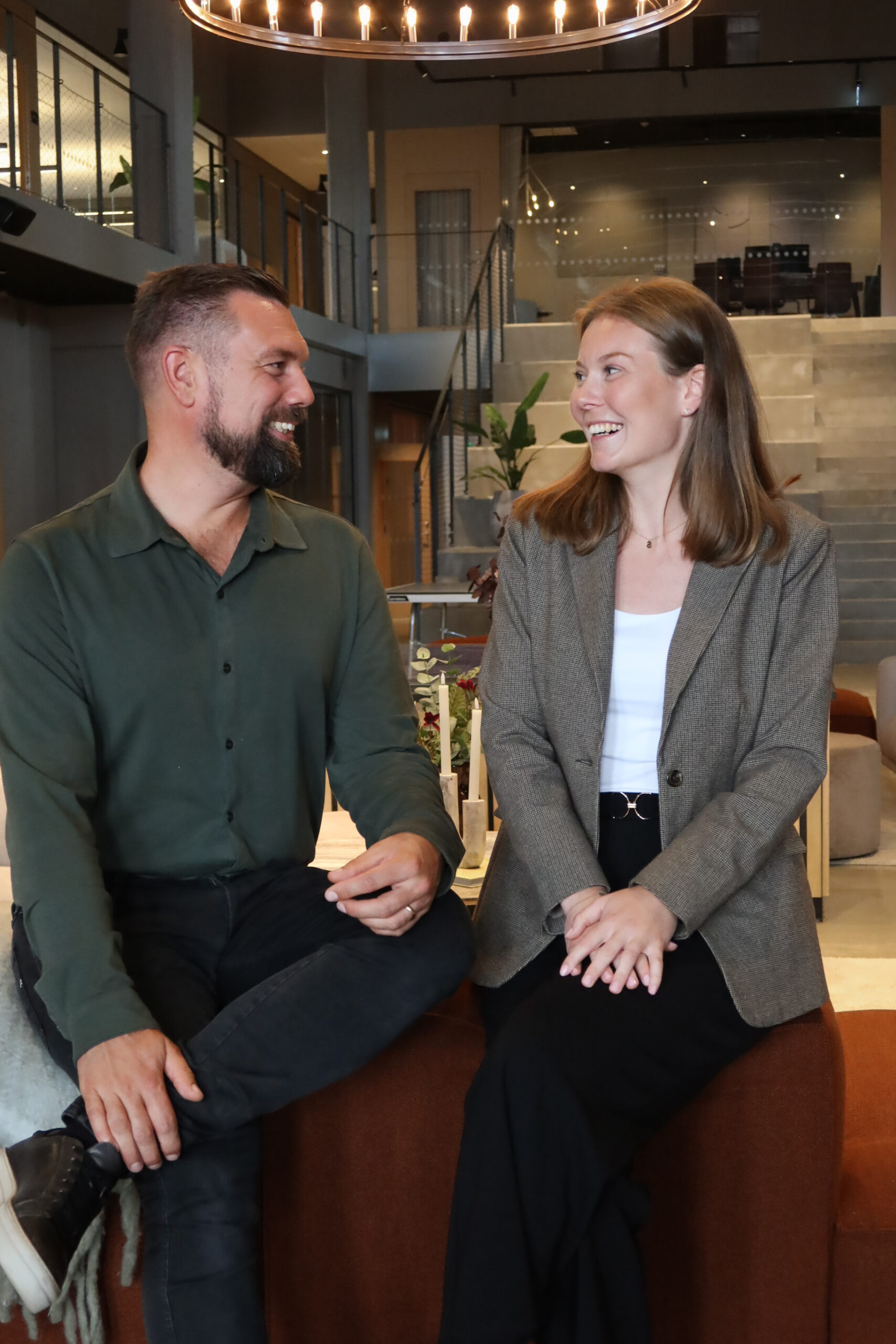 Anna Erlandsson och Fredrik Bardon sitter på soffan, tittar på varandra och skrattar